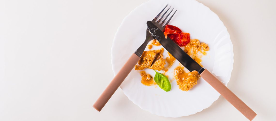 Stop food waste. Close up of leftover food on a plate after dinner on the table top view